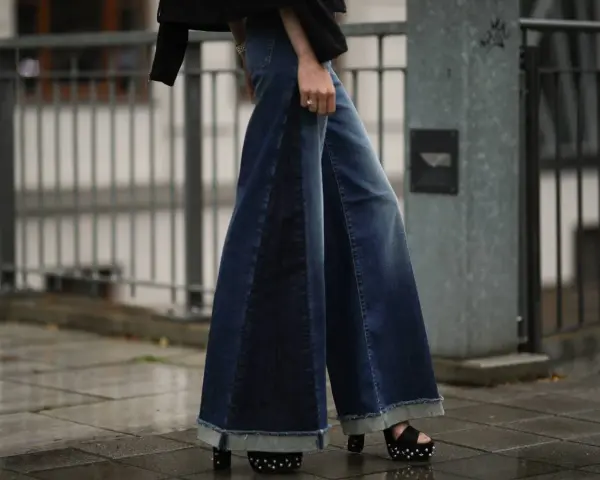 Woman wearing wide-leg denim palazzo pants with frayed hems and platform sandals.