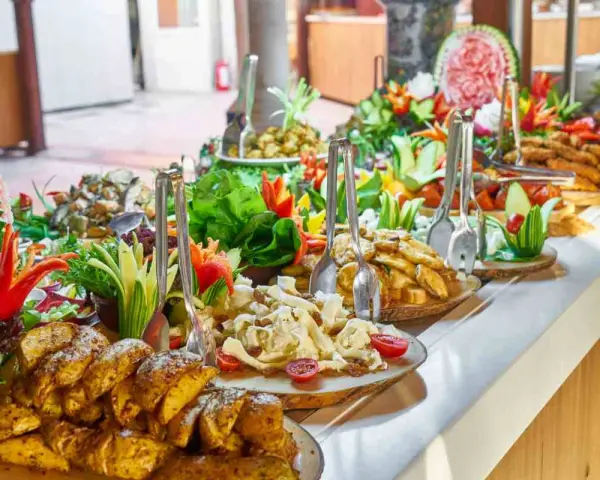 Buffet con patate arrosto, insalate fresche e frutta intagliata. Ecco come mettere la tovaglia per buffet, creando un'atmosfera invitante.