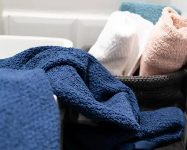 Asciugamani spugna blu, bianchi, rosa e azzurri in un cesto. Il primo lavaggio li rende ancora più soffici e pronti all'uso.
