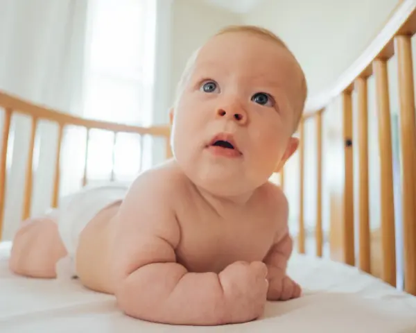 Bambino in culla, con pannolino, che esplora il mondo. Le misure lenzuolino culla sono perfette per questo piccolo esploratore.