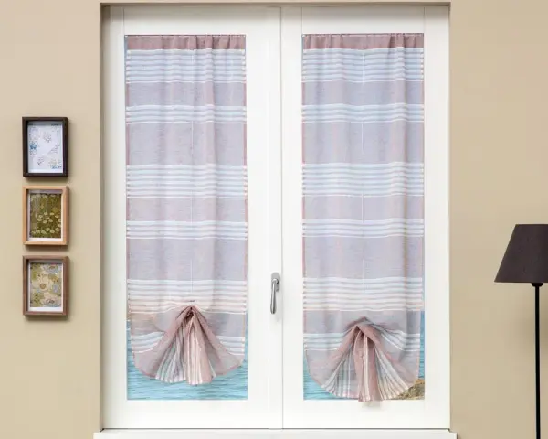 Tende a righe attaccate alla finestra, con un nodo decorativo sul fondo. Tre quadretti appesi alla parete.