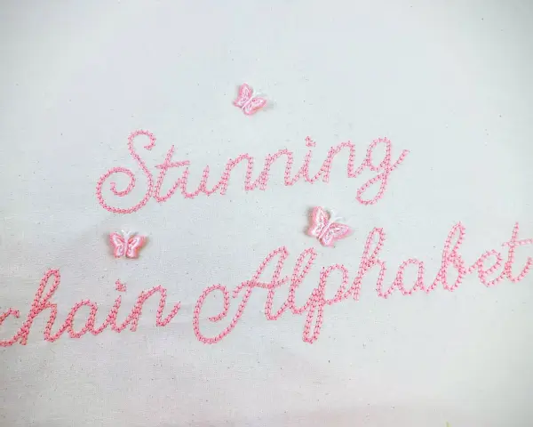 Punto ricamo per scritte: "Stunning chain Alphabet" in rosa, con piccole farfalle applicate.