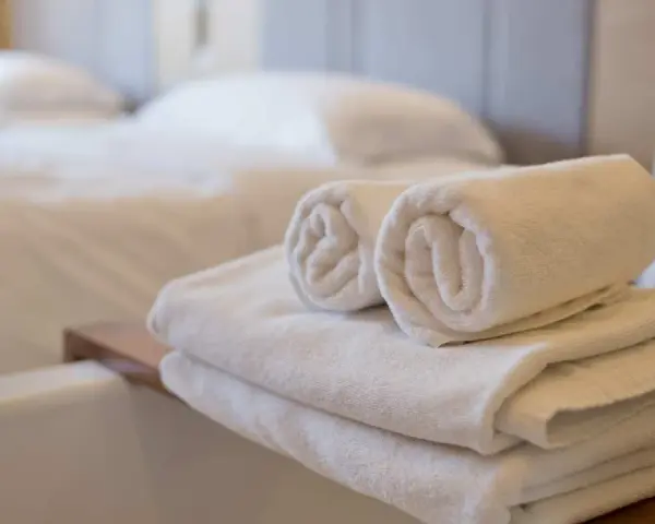 Asciugamani bianchi piegati e arrotolati, pronti per l'uso. Le misure asciugamani sono perfette per un bagno accogliente.