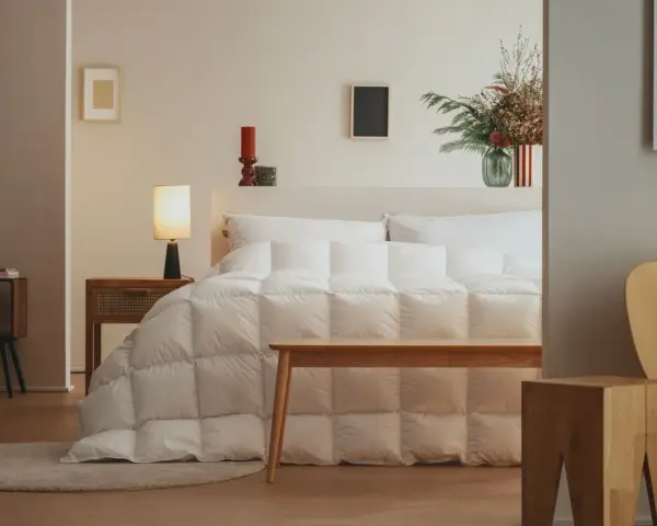 Un letto accogliente con un piumone bianco trapuntato, pronto per accogliere la parte tonda del piumone dove va, creando un nido perfetto.