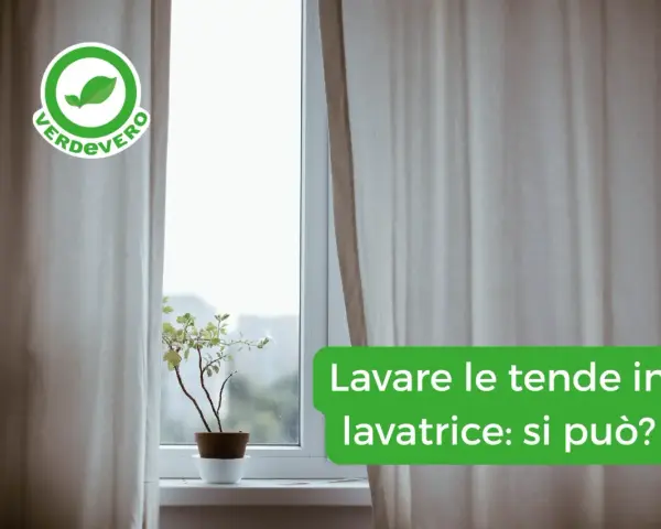 Tende chiare drappeggiate su una finestra, con una pianta in vaso sul davanzale. Il testo chiede: "Lavare le tende in lavatrice: si può?".