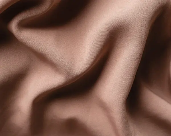 Tessuto di raso color tortora, morbido e drappeggiato, che mostra la sua texture fine. Il raso si può stirare per ottenere una finitura impeccabile.
