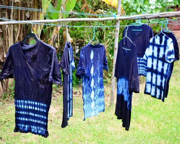 Abiti con motivi tie-dye blu e bianchi, pronti per asciugare dopo aver provato a tingere tessuti sintetici.