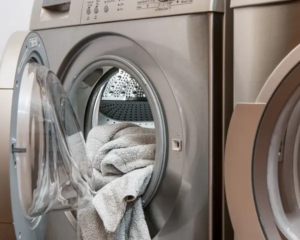 Lavatrice con un tappeto grigio all'interno, pronta per il lavaggio. Scopri come lavare i tappeti in lavatrice per mantenerli freschi e puliti.