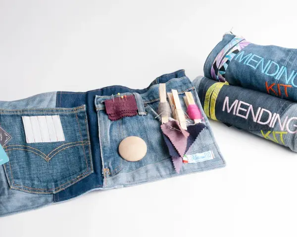 Kit per rammendo creativo jeans: tasche con fili, aghi, tessuti e bottoni. Arrotolati, altri kit con scritta "Mending Kit".