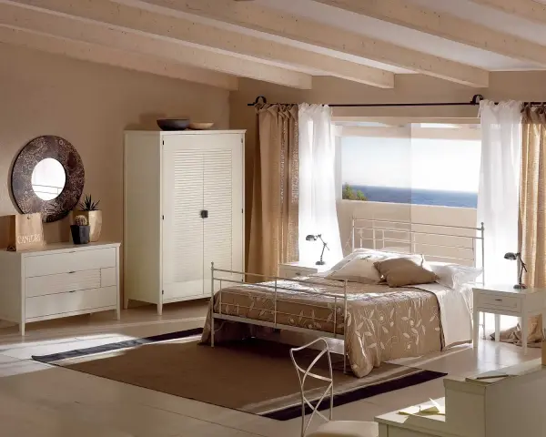 Camera da letto con letto tortora, armadio bianco e cassettiera. Abbinamenti eleganti per un ambiente rilassante con vista mare.