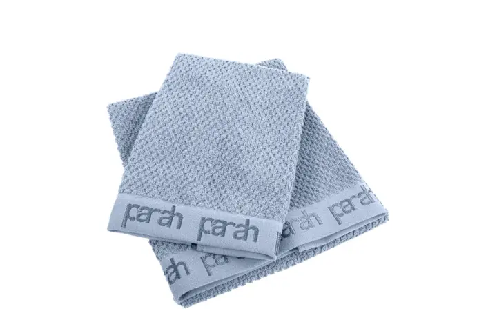 Due asciugamani azzurri con logo "parah" sovrapposti. Sembrano morbidi, ma chissà se sono asciugamani che non asciugano.