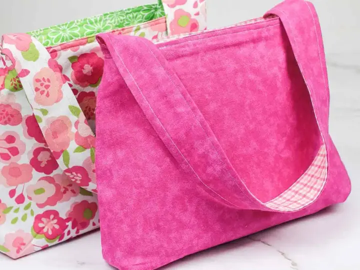 Two handmade fabric bags, one pink with a floral pattern, the other solid pink with a plaid lining.