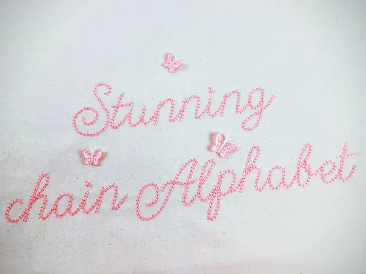 Punto ricamo per scritte: "Stunning chain Alphabet" in rosa, con piccole farfalle applicate.
