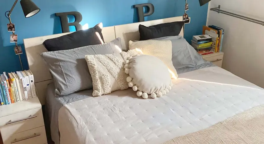 Letto con cuscini morbidi e coperta beige. Impara come fare il letto per un risveglio sereno.
