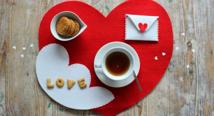 Tovagliette colazione fai da te a forma di cuore, con biscotti, tè e una busta decorata.