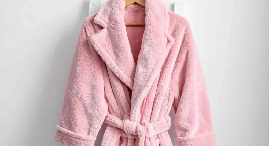 Accappatoio rosa soffice appeso. Scopri come lavare accappatoio in lavatrice per mantenerlo morbido e profumato.