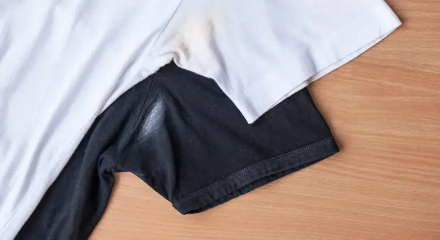 Yellow underarm stains on a white t-shirt and a white residue on a black t-shirt.