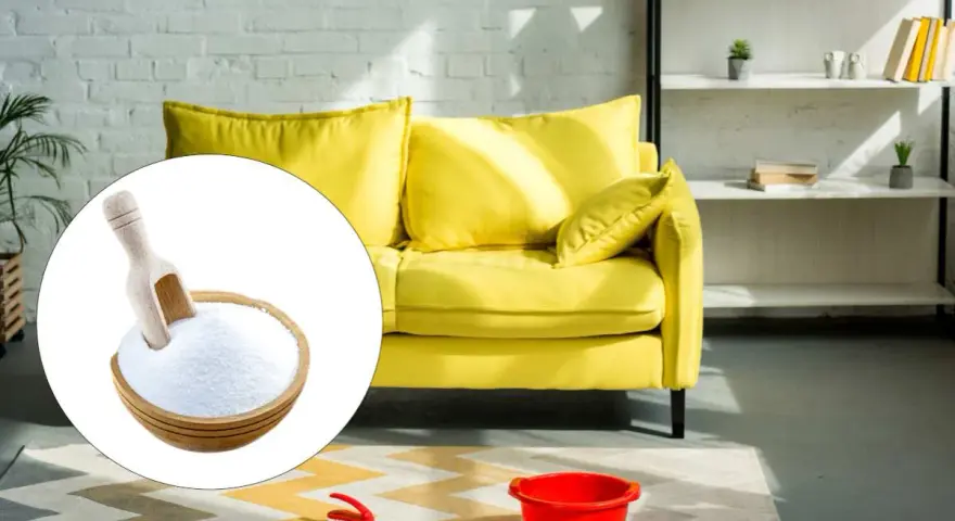 A bowl of baking soda with a scoop, next to a yellow sofa and cleaning supplies.