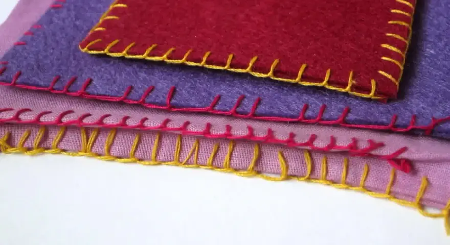 Tessuti colorati sovrapposti, rifiniti con un punto coperta giallo, rosa e rosso.