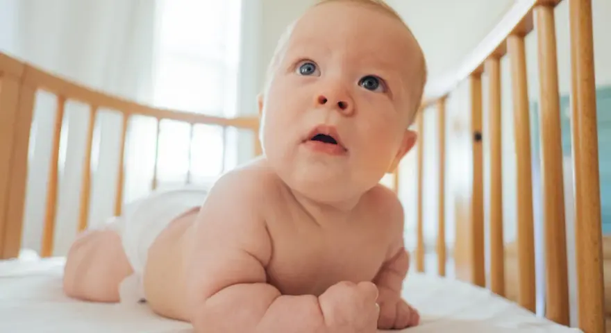 Bambino in culla, con pannolino, che esplora il mondo. Le misure lenzuolino culla sono perfette per questo piccolo esploratore.