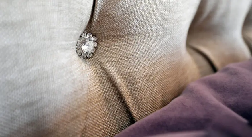 Tessuto per rivestimenti con un bottone decorativo tempestato di strass.