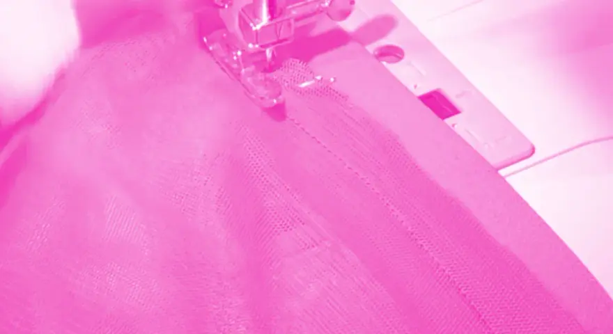 Macchina da cucire al lavoro per cucire una gonna di tulle rosa.