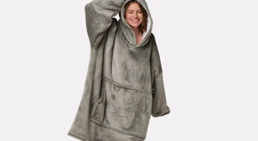 Donna sorridente indossa una felpa oversize grigia, morbida e confortevole, perfetta per chi cerca come ammorbidire tessuti rigidi e godersi il relax.