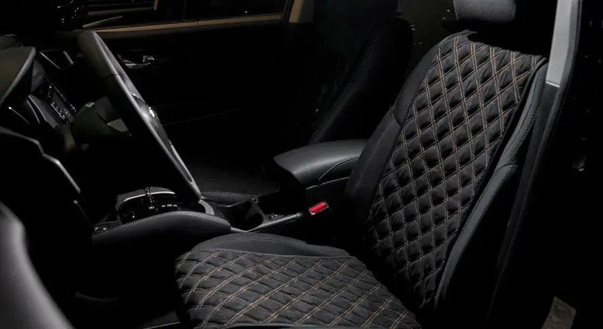 Interno auto con sedili neri trapuntati, il miglior tessuto per sedili auto per un comfort elegante.