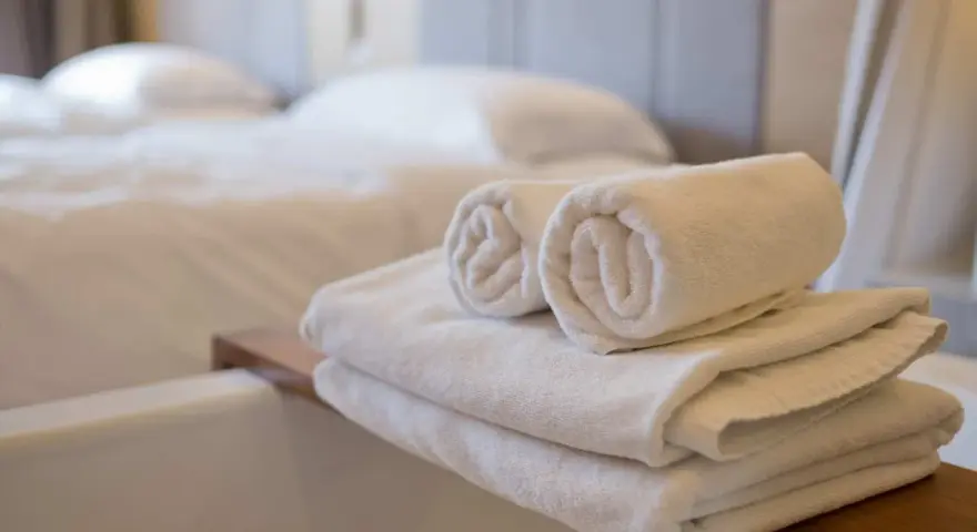 Asciugamani bianchi piegati e arrotolati, pronti per l'uso. Le misure asciugamani sono perfette per un bagno accogliente.