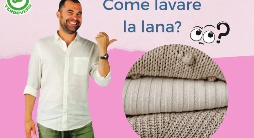 Uomo sorridente indica come lavare lana a mano. Pile di maglioni in primo piano.