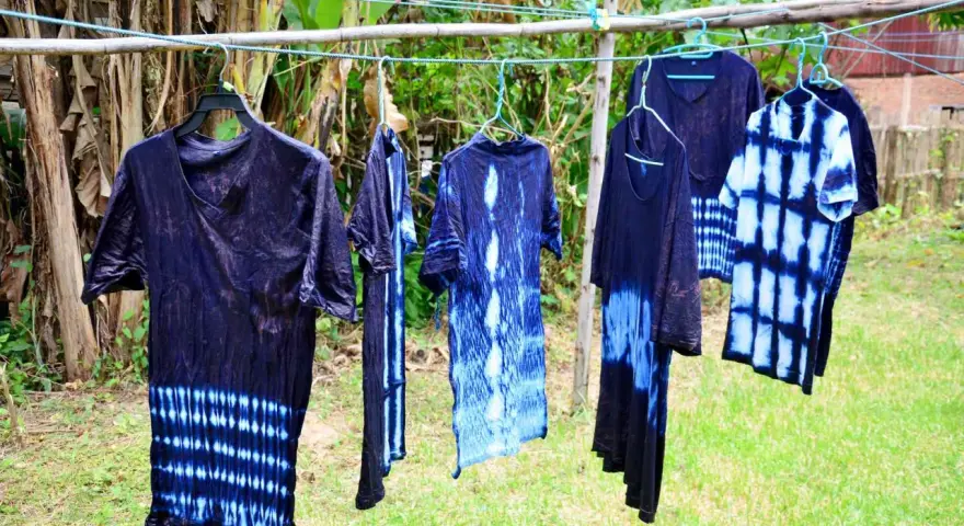 Abiti con motivi tie-dye blu e bianchi, pronti per asciugare dopo aver provato a tingere tessuti sintetici.