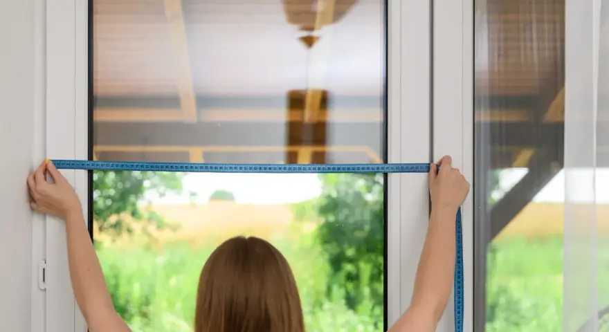 Persona effettua le misure tende a vetro con un metro a nastro blu, per un risultato perfetto.