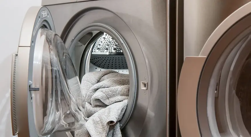 Lavatrice con un tappeto grigio all'interno, pronta per il lavaggio. Scopri come lavare i tappeti in lavatrice per mantenerli freschi e puliti.
