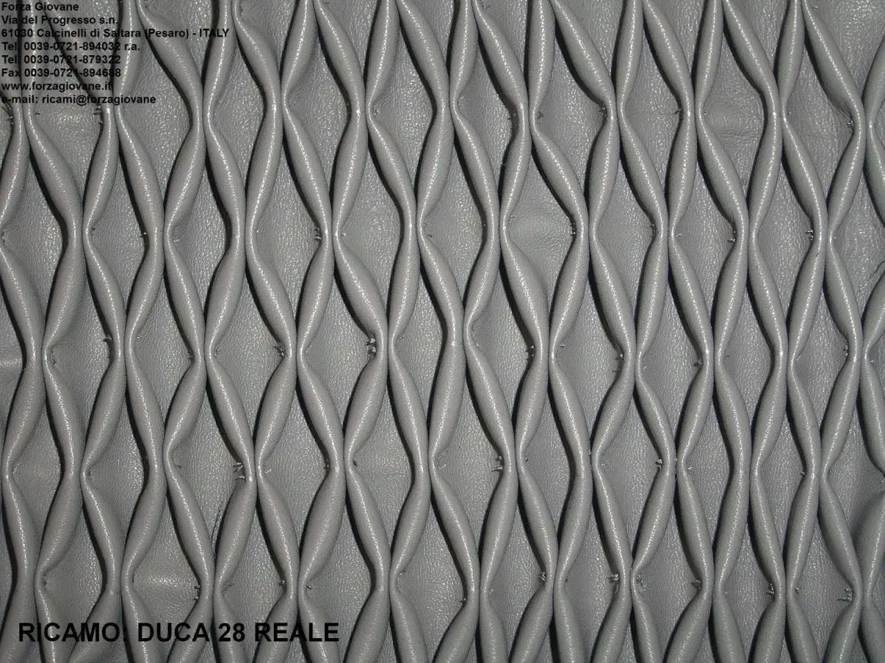 Ricamo in pelle grigia con un motivo a nido d'ape, che crea un effetto tridimensionale e geometrico.