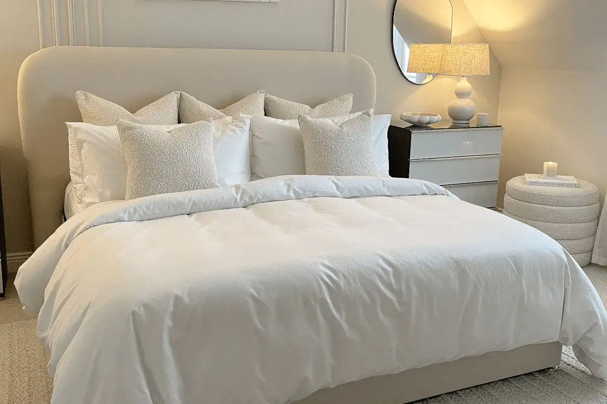 Letto bianco impeccabile con cuscini testurizzati, un esempio di come rifare il letto in modo elegante per un'atmosfera serena.