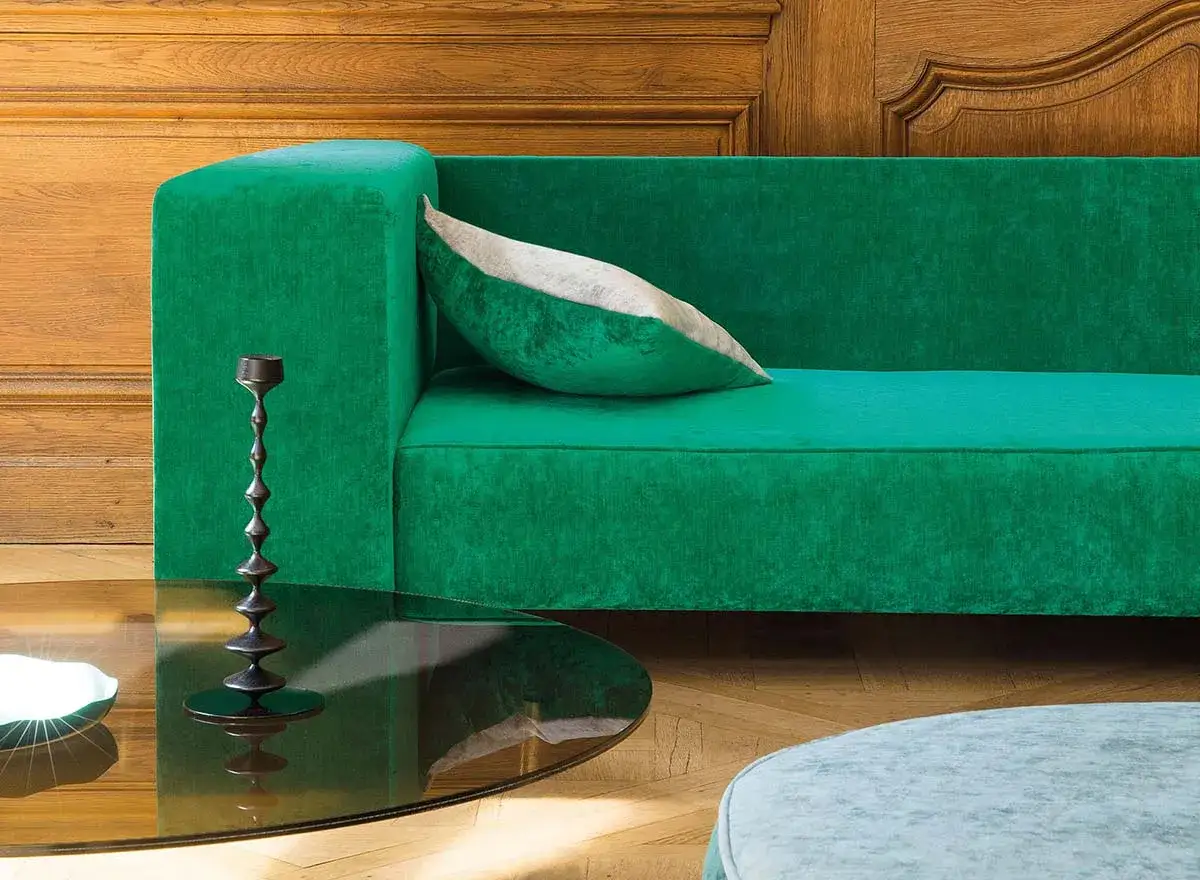 Divano verde smeraldo con cuscino decorativo. Il lussuoso tessuto per rivestimenti in velluto cattura la luce, creando un'atmosfera accogliente.