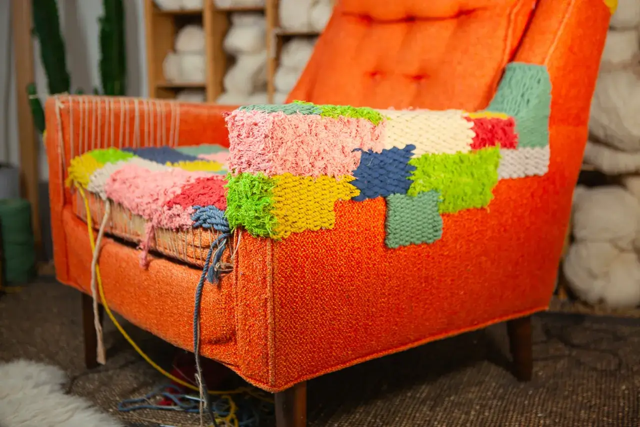 Un vecchio poltrone arancione viene trasformato con un colorato patchwork di ricamo, rammendare un buco con creatività.