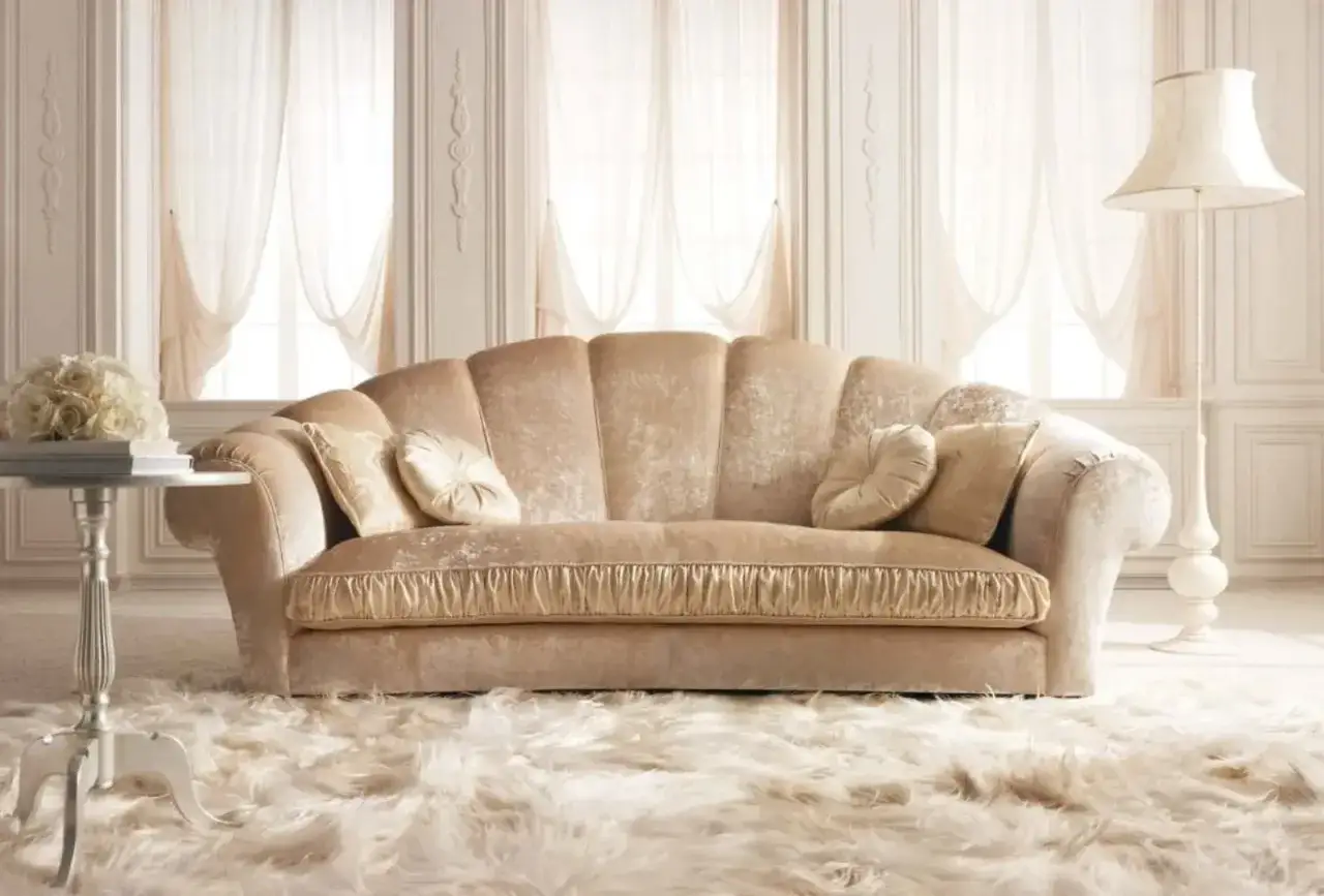 Divano elegante color champagne, con cuscini decorativi e un tappeto soffice. Un esempio di come coprire un divano in modo elegante con stile e raffinatezza.