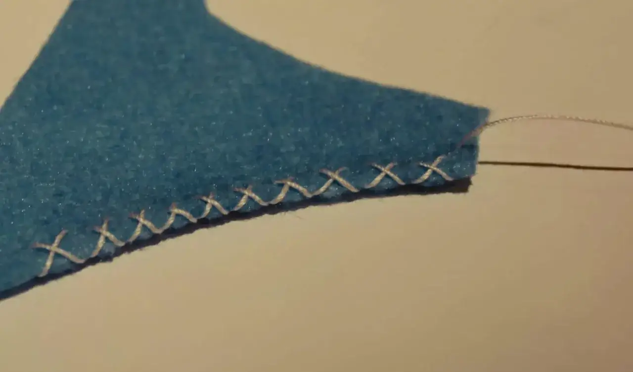 Bordo di feltro azzurro rifinito con un punto overlock a mano, creando una linea di 