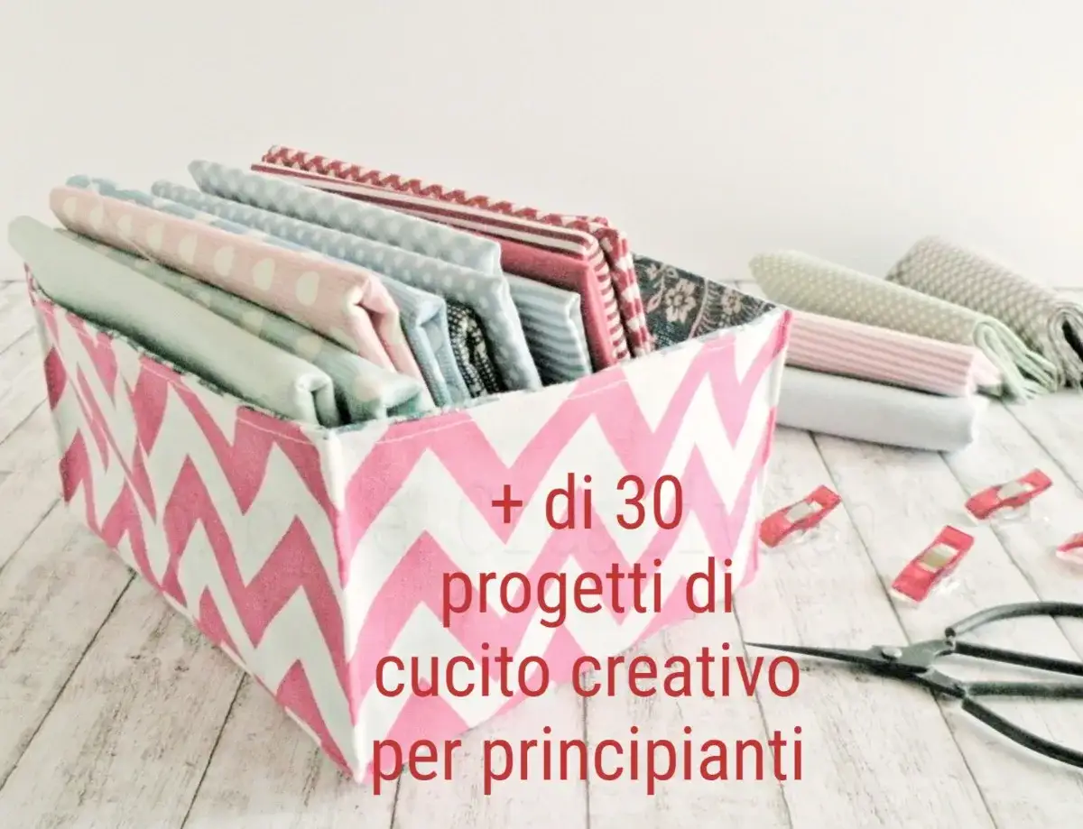 Cesto con tessuti colorati per progetti di cucito creativo. Forbici e clip da cucito completano la scena.