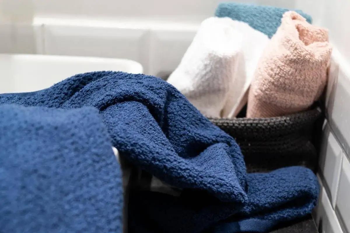 Asciugamani spugna blu, bianchi, rosa e azzurri pronti per il primo lavaggio. Morbidi e soffici, in un cesto.