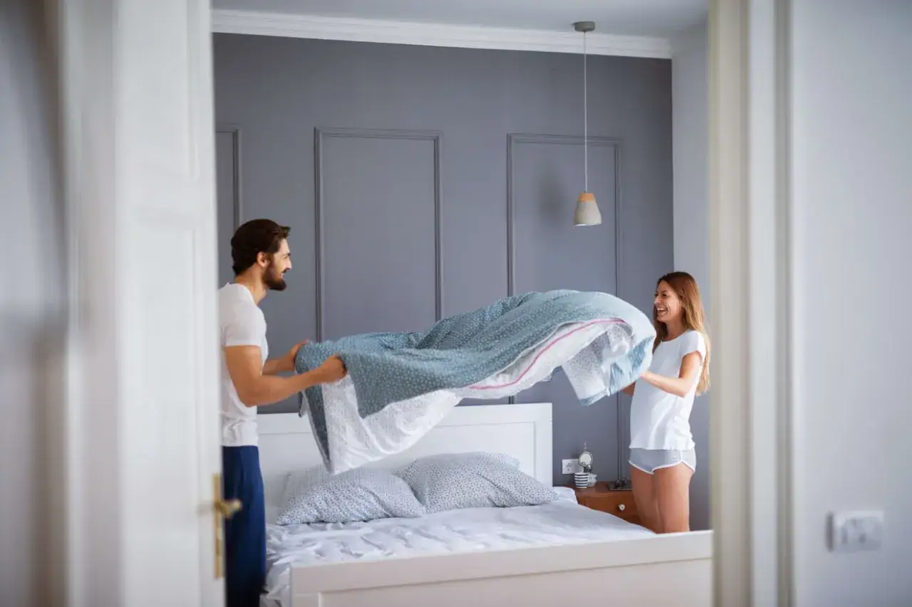 Coppia felice cambia le lenzuola, un promemoria su ogni quanto cambiare le lenzuola per un sonno sano.
