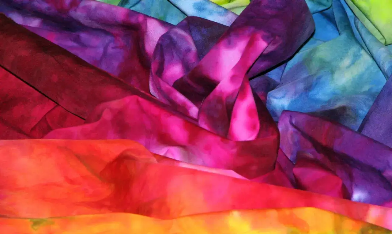 Tessuti colorati con sfumature vivaci, un esempio di come tingere i tessuti con tecniche tie-dye.