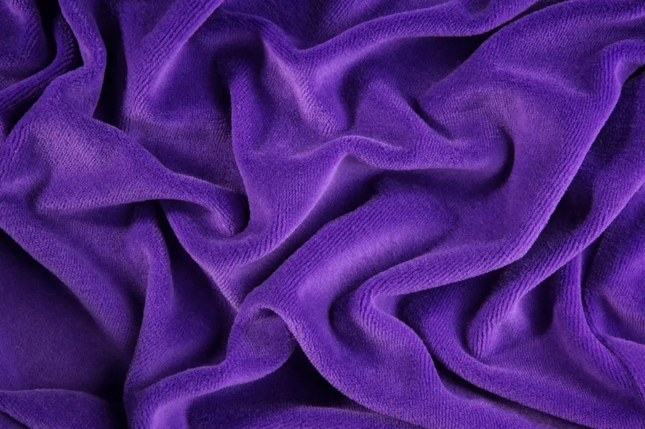Tessuto di velluto viola drappeggiato, morbido e soffice. Scopri come lavare il velluto per mantenerlo sempre come nuovo.