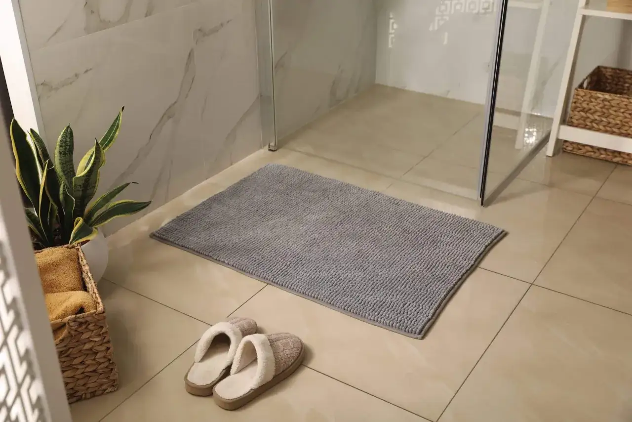 Tappeto da bagno grigio e pantofole morbide, pronti per essere lavati in lavatrice.