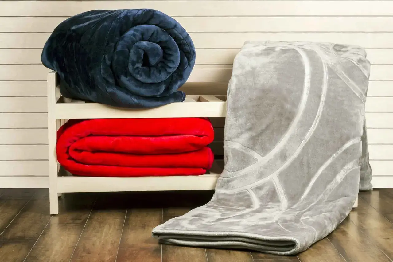 Coperte morbide, una blu arrotolata, due rosse piegate e una grigia con motivi geometrici. Perfette per lavare pile in lavatrice e mantenere tutto fresco.