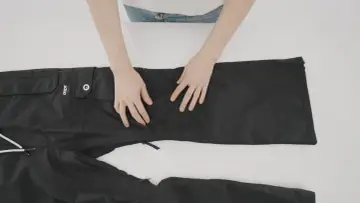 Mani che preparano un buco nei pantaloni neri per rammendare.