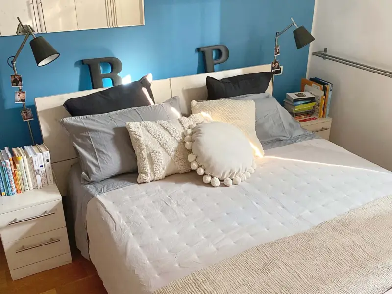 Letto con cuscini morbidi e coperta beige. Impara come fare il letto per un risveglio sereno.