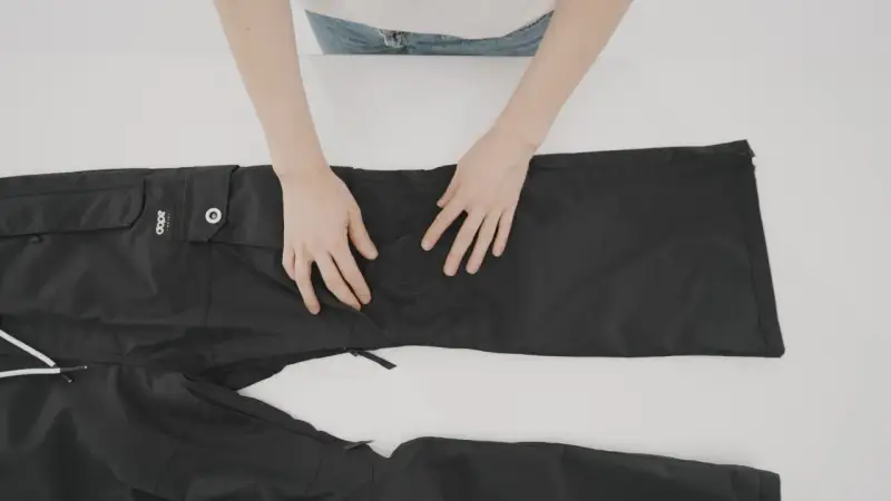 Mani che preparano un buco nei pantaloni neri per rammendare.